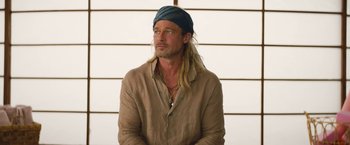 Movie still from “The Lost City” (2022), directed by Aaron Nee – A man with long blonde hair wearing a blue hat; Close Up shot, Low angle