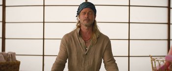 Movie still from “The Lost City” (2022), directed by Aaron Nee – A man with long blonde hair wearing a head scarf; Close Up shot, High angle
