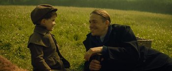 Movie still from “The Lost City of Z” (2016), directed by James Gray – A man and a boy sitting in the grass talking to each other; Medium shot, Over the shoulder angle