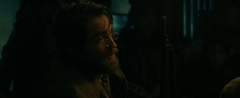 Movie still from “The Lost City of Z” (2016), directed by James Gray – A man with a beard and glasses is sitting in a dark room; Close Up shot, Over the shoulder angle