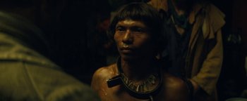 Movie still from “The Lost City of Z” (2016), directed by James Gray – A man wearing a necklace is looking into the camera; Close Up shot, Over the shoulder angle