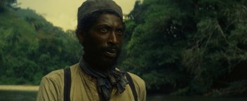 Movie still from “The Lost City of Z” (2016), directed by James Gray – A man with a beard and a hat is standing in front of trees; Close Up shot, High angle