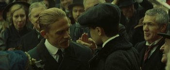Movie still from “The Lost City of Z” (2016), directed by James Gray – A man in a suit and hat talking to another man in a suit and hat; Close Up shot, Over the shoulder angle