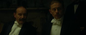 Movie still from “The Lost City of Z” (2016), directed by James Gray – A man wearing a tuxedo and a bow tie; Close Up shot, Low angle