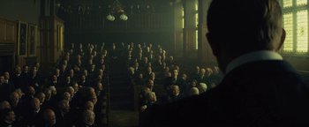 Movie still from “The Lost City of Z” (2016), directed by James Gray – An audience is sitting in a dark room; Wide shot, Low angle