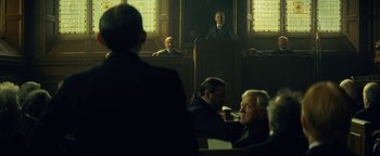 Movie still from “The Lost City of Z” (2016), directed by James Gray – Three men are sitting in front of a judge in a courtroom; Medium shot, Over the shoulder angle