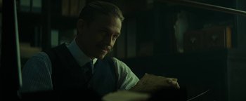 Movie still from “The Lost City of Z” (2016), directed by James Gray – A man sitting at a table holding a piece of paper; Close Up shot, Over the shoulder angle