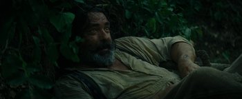 Movie still from “The Lost City of Z” (2016), directed by James Gray – A man with a long beard sitting in the woods; Medium shot, Low angle