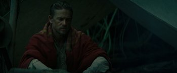 Movie still from “The Lost City of Z” (2016), directed by James Gray – A man sitting in front of a wall with a blanket on; Medium shot, Over the shoulder angle