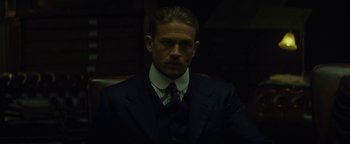 Movie still from “The Lost City of Z” (2016), directed by James Gray – A man in a suit and tie sitting in a chair; Close Up shot, Over the shoulder angle