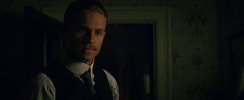 Movie still from “The Lost City of Z” (2016), directed by James Gray – A man in a suit and tie standing in front of a window; Close Up shot, Low angle