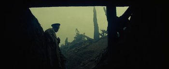 Movie still from “The Lost City of Z” (2016), directed by James Gray – A man in a trench coat standing next to trees; Wide shot, Low angle