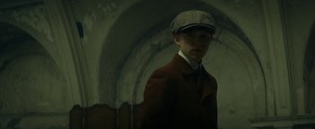 Movie still from “The Lost City of Z” (2016), directed by James Gray – A young man in a hat and a coat; Close Up shot, Low angle