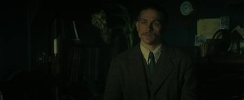 Movie still from “The Lost City of Z” (2016), directed by James Gray – A man in a suit standing in a dark room; Close Up shot, Over the shoulder angle