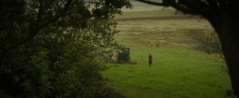 Movie still from “The Lost City of Z” (2016), directed by James Gray – Two people standing next to a horse drawn carriage in a field; Extreme Wide shot, High angle