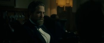 Movie still from “The Lost City of Z” (2016), directed by James Gray – A man with a beard wearing a suit and tie; Medium shot, Over the shoulder angle