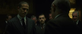 Movie still from “The Lost City of Z” (2016), directed by James Gray – A group of men standing next to each other in suits; Medium shot, Over the shoulder angle