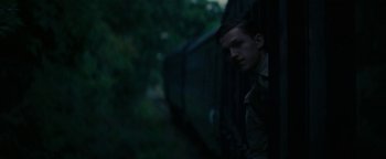 Movie still from “The Lost City of Z” (2016), directed by James Gray – A man standing next to a train on a train track; Medium shot, Low angle