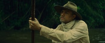Movie still from “The Lost City of Z” (2016), directed by James Gray – A man in a hat holding onto a pole; Medium shot, Over the shoulder angle