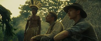 Movie still from “The Lost City of Z” (2016), directed by James Gray – A group of men sitting next to each other in a forest; Medium shot, Low angle