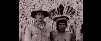 Movie still from “The Lost City of Z” (2016), directed by James Gray – A man standing next to a man wearing a hat; Medium shot, Low angle