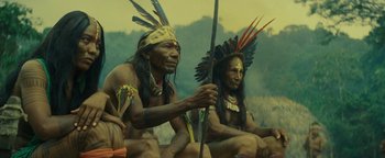 Movie still from “The Lost City of Z” (2016), directed by James Gray – A couple of native americans sitting next to each other; Medium shot, Low angle