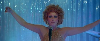 Movie still from “The Lure” (2015), directed by Agnieszka Smoczynska – A woman with curly hair is holding a microphone in front of her; Close Up shot, Low angle