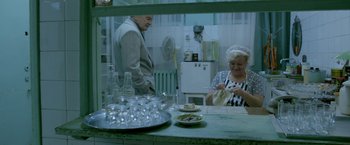 Movie still from “The Lure” (2015), directed by Agnieszka Smoczynska – An older man and a woman in a kitchen; Medium shot, High angle