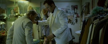 Movie still from “The Lure” (2015), directed by Agnieszka Smoczynska – A man in a white suit is getting his hair cut by a woman; Medium shot, Over the shoulder angle