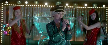 Movie still from “The Lure” (2015), directed by Agnieszka Smoczynska – A woman wearing a hat and holding a microphone in her hand; Medium shot, Low angle