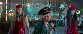 Movie still from “The Lure” (2015), directed by Agnieszka Smoczynska – A woman in a hat is holding a microphone; Medium shot, Over the shoulder angle