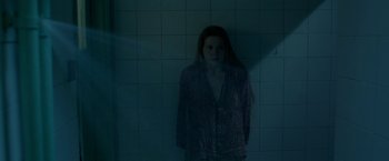 Movie still from “The Lure” (2015), directed by Agnieszka Smoczynska – A woman standing next to a tiled wall in a dark room; Medium shot, Low angle