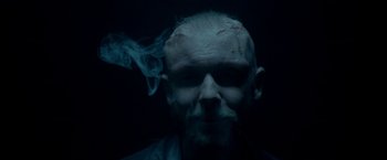 Movie still from “The Lure” (2015), directed by Agnieszka Smoczynska – A man with a beard smoking in a dark room; Close Up shot, Overhead angle