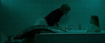 Movie still from “The Lure” (2015), directed by Agnieszka Smoczynska – A man in black shirt and white apron leaning over a sink; Wide shot, High angle