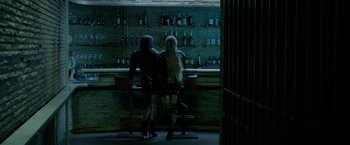 Movie still from “The Lure” (2015), directed by Agnieszka Smoczynska – Two people sitting at a bar in front of a wall of liquor bottles; Wide shot, Over the shoulder angle