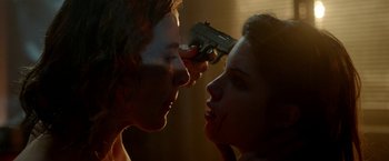 Movie still from “The Lure” (2015), directed by Agnieszka Smoczynska – A man and a woman face each other with a gun pointed at them; Close Up shot, Over the shoulder angle