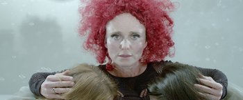 Movie still from “The Lure” (2015), directed by Agnieszka Smoczynska – A woman with red curly hair holding two cats in her arms; Close Up shot, Overhead angle