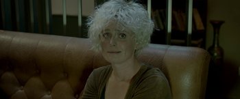 Movie still from “The Lure” (2015), directed by Agnieszka Smoczynska – A woman sitting on top of a brown leather couch; Close Up shot, High angle