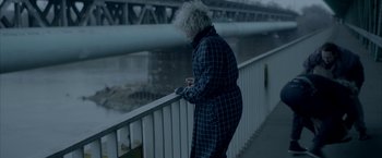 Movie still from “The Lure” (2015), directed by Agnieszka Smoczynska – An older woman standing next to a railing on a bridge; Medium shot, High angle