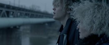 Movie still from “The Lure” (2015), directed by Agnieszka Smoczynska – A young man with blonde curly hair looking out a window; Close Up shot, Over the shoulder angle