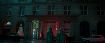 Movie still from “The Lure” (2015), directed by Agnieszka Smoczynska – Two people in hooded jackets standing in front of a building at night; Extreme Wide shot, Low angle