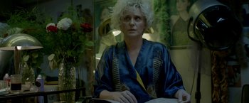 Movie still from “The Lure” (2015), directed by Agnieszka Smoczynska – A woman in a blue robe sitting at a table; Close Up shot, Low angle