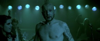 Movie still from “The Lure” (2015), directed by Agnieszka Smoczynska – A man with a beard and a mohawk is standing; Close Up shot, Over the shoulder angle