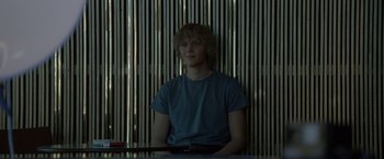 Movie still from “The Lure” (2015), directed by Agnieszka Smoczynska – A man sitting in front of a wooden wall; Medium shot, Over the shoulder angle