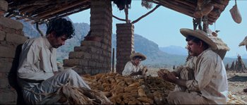 Movie still from “The Magnificent Seven” (1960), directed by John Sturges – A man sitting on top of a pile of corn stalks; Wide shot, Low angle