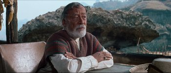 Movie still from “The Magnificent Seven” (1960), directed by John Sturges – An old man with a beard and a sweater on; Medium shot, Over the shoulder angle