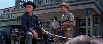 Movie still from “The Magnificent Seven” (1960), directed by John Sturges – Two men sitting on top of a horse drawn carriage; Medium shot, Low angle