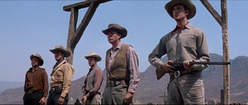 Movie still from “The Magnificent Seven” (1960), directed by John Sturges – A group of men standing next to each other holding guns; Medium shot, Low angle