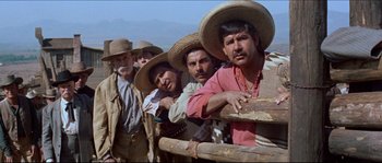 Movie still from “The Magnificent Seven” (1960), directed by John Sturges – A group of men standing next to each other wearing straw hats; Medium shot, Low angle