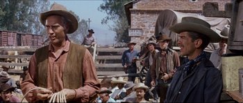 Movie still from “The Magnificent Seven” (1960), directed by John Sturges – A group of men standing next to each other on a field; Medium shot, Over the shoulder angle